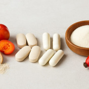 Verschiedene Vitamin-C-Präparate, darunter Acerola-Kirschen, Kapseln, Tabletten, Hagebutten und Fruchtpulver, auf einem hellen Hintergrund arrangiert.