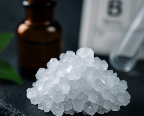 Was Bor im Körper bewirkt – Fakten & Studien kompakt 2 Makroaufnahme von weißen Borax-Kristallen vor einem Apothekerfläschchen und dem Elementsymbol für Bor – Symbolbild für naturheilkundliche Anwendung