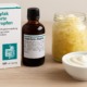 Hylak forte Tropfen mit Verpackung, daneben Glas mit Sauerkraut und Schale Joghurt auf Holzoberfläche.