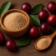 Camu-Camu-Früchte mit grünem Blattwerk neben Holzschälchen und Löffel mit Camu-Camu-Pulver auf Holztisch.
